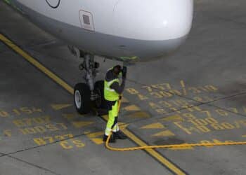 A ground crew member connects a fuel hose to an Airbus A321 aircraft