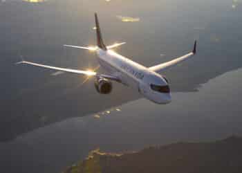 An Air Canada plane flies over land and water