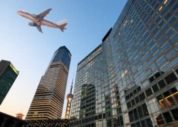 An airplane flies over skyscrapers in Shanghai