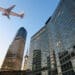 An airplane flies over skyscrapers in Shanghai